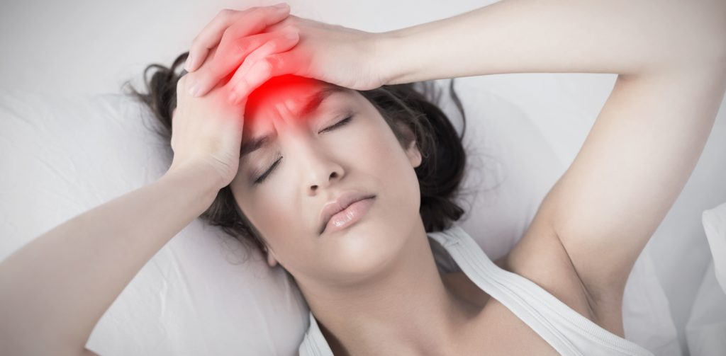 mulher deitada com a mão na cabeça em vermelho indicando dores de cabeça
