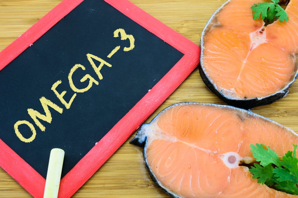 Filés de salmão e um quadro de giz com a escrita "omega 3"