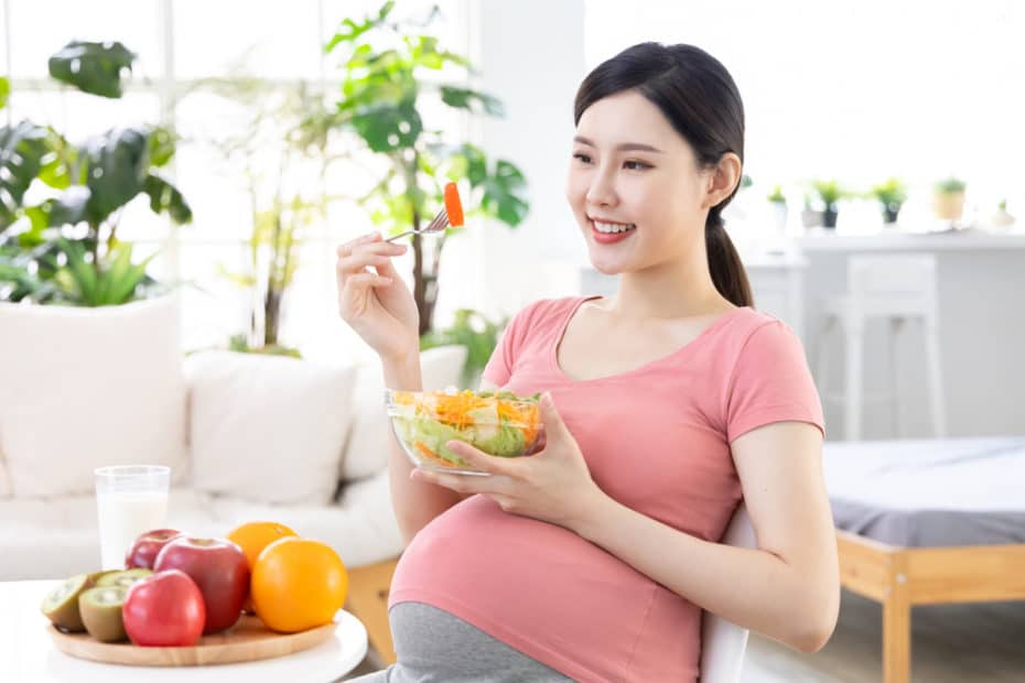 Dieta para gestante. Mulher grávida comendo frutas.