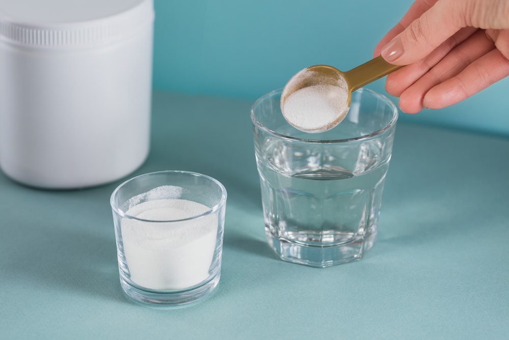 Misturando ácido hialurônico em pó em um copo com água para suplementação oral.