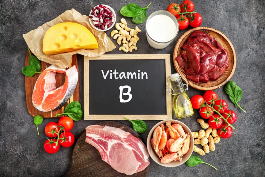 Alimentos fontes de vitamina do complexo b ao redor de uma lousa preta escrito vitamina B em giz branco
