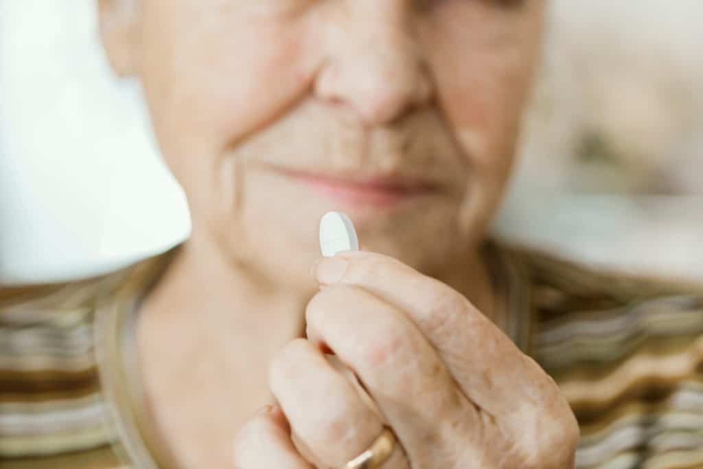 mulher idosa consumindo uma cápsula de suplemento