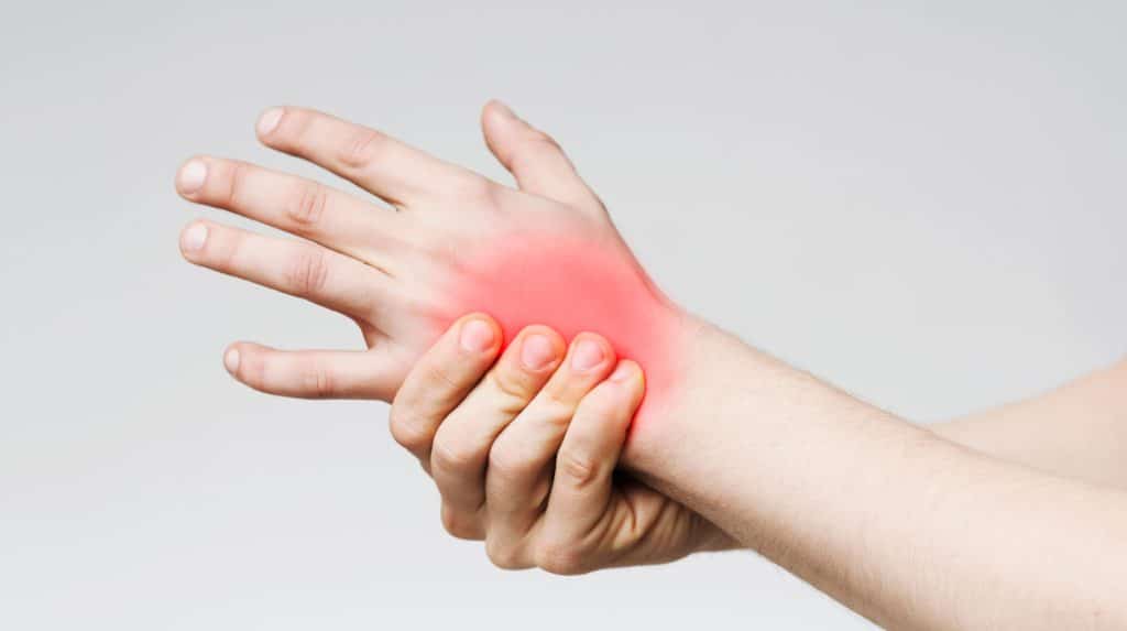 mão com região vermelha no pulso indicando dores por artrite reumatoide