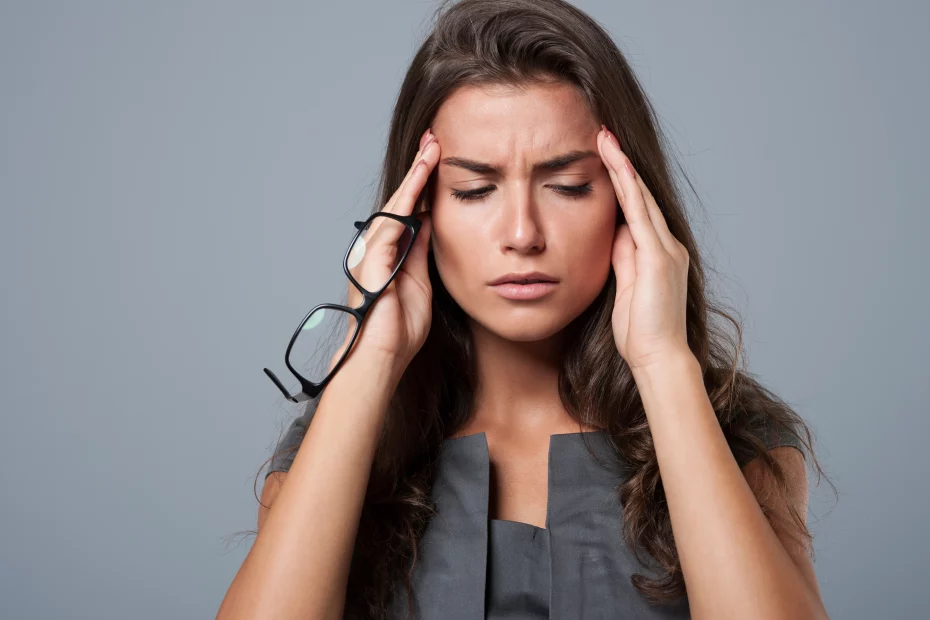 mulher com as mãos na cabeça indicando dor de cabeça | alimentos que causam enxaqueca